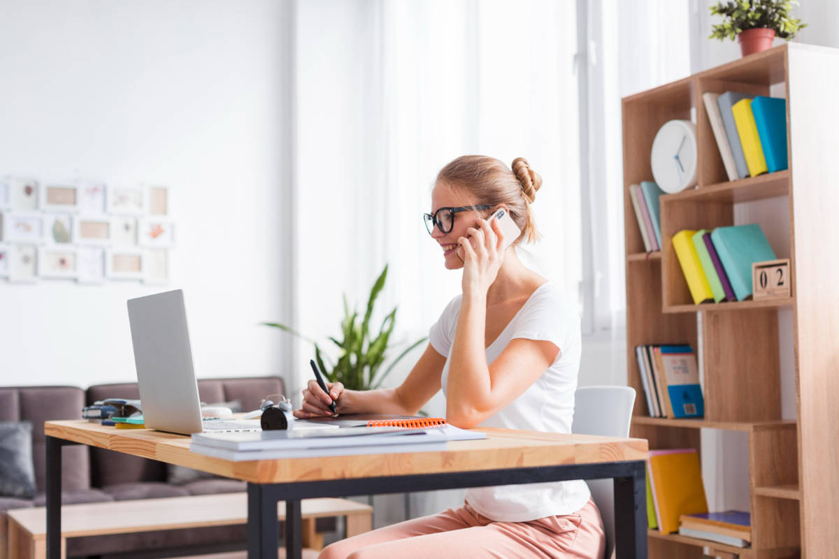 Frau arbeitet am Laptop und telefoniert